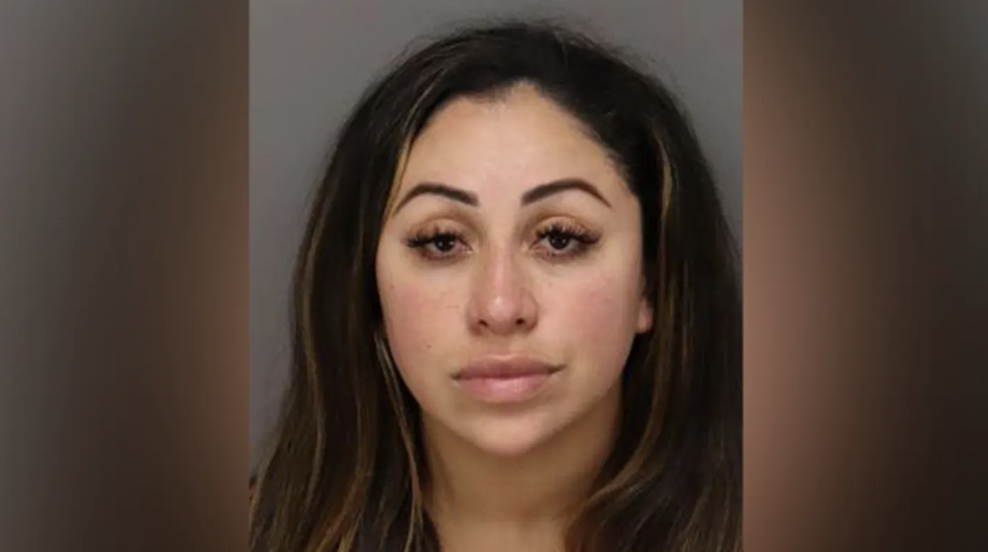 A woman with long dark hair and a neutral expression against a plain background.