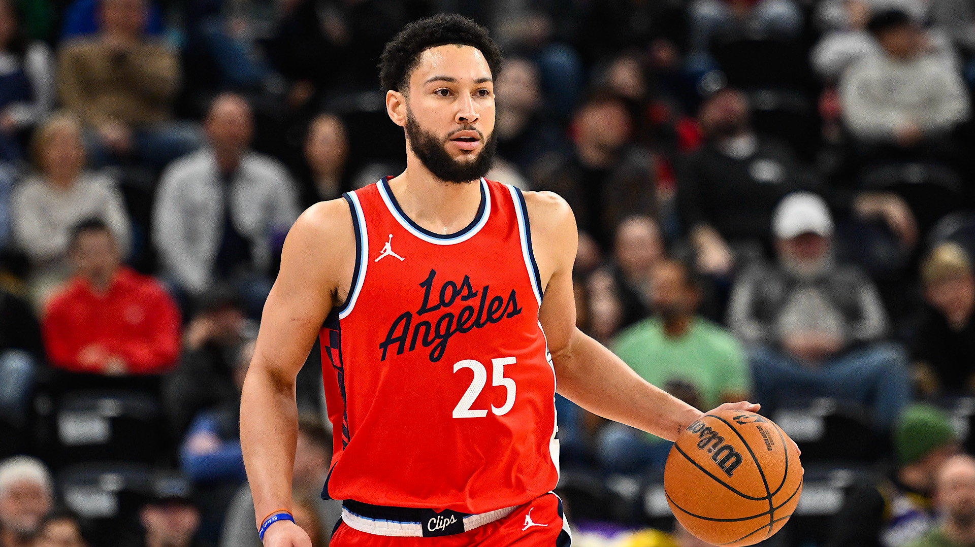 A basketball player in a red Los Angeles jersey, number 25, dribbles a ball on the court.
