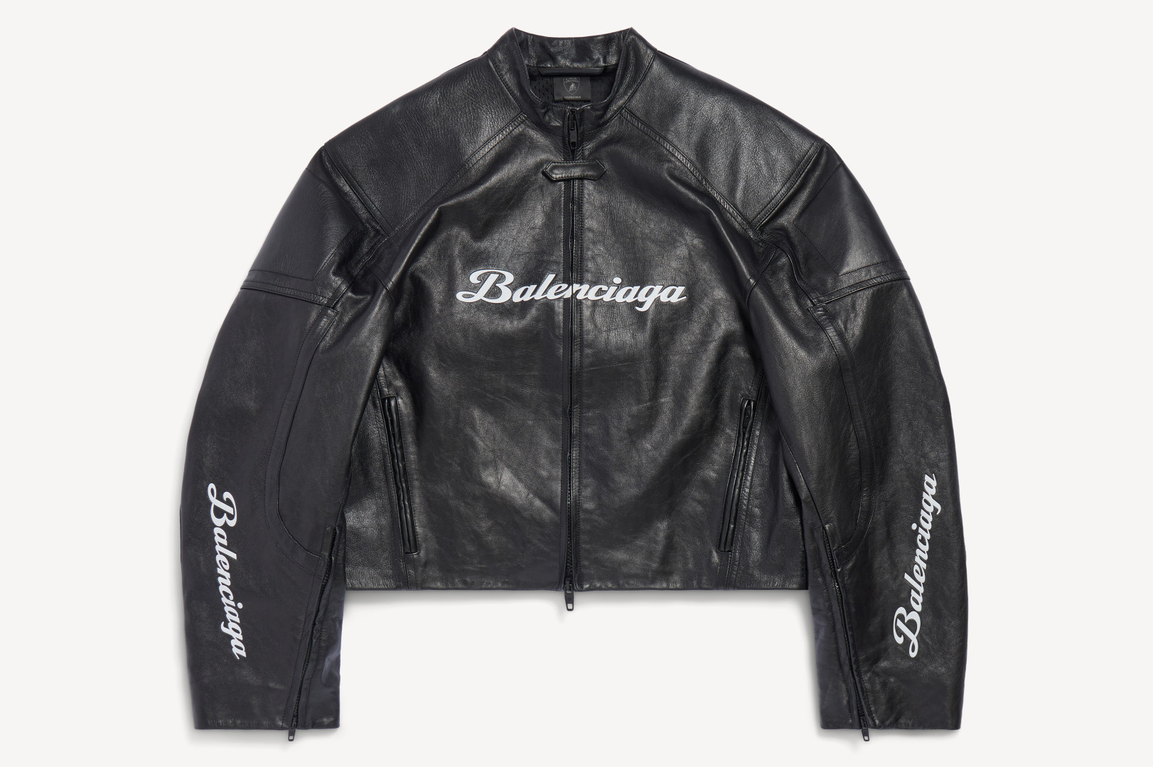 A black leather Balenciaga jacket with white logo text on the chest and sleeves, featuring a front zipper and two side pockets.