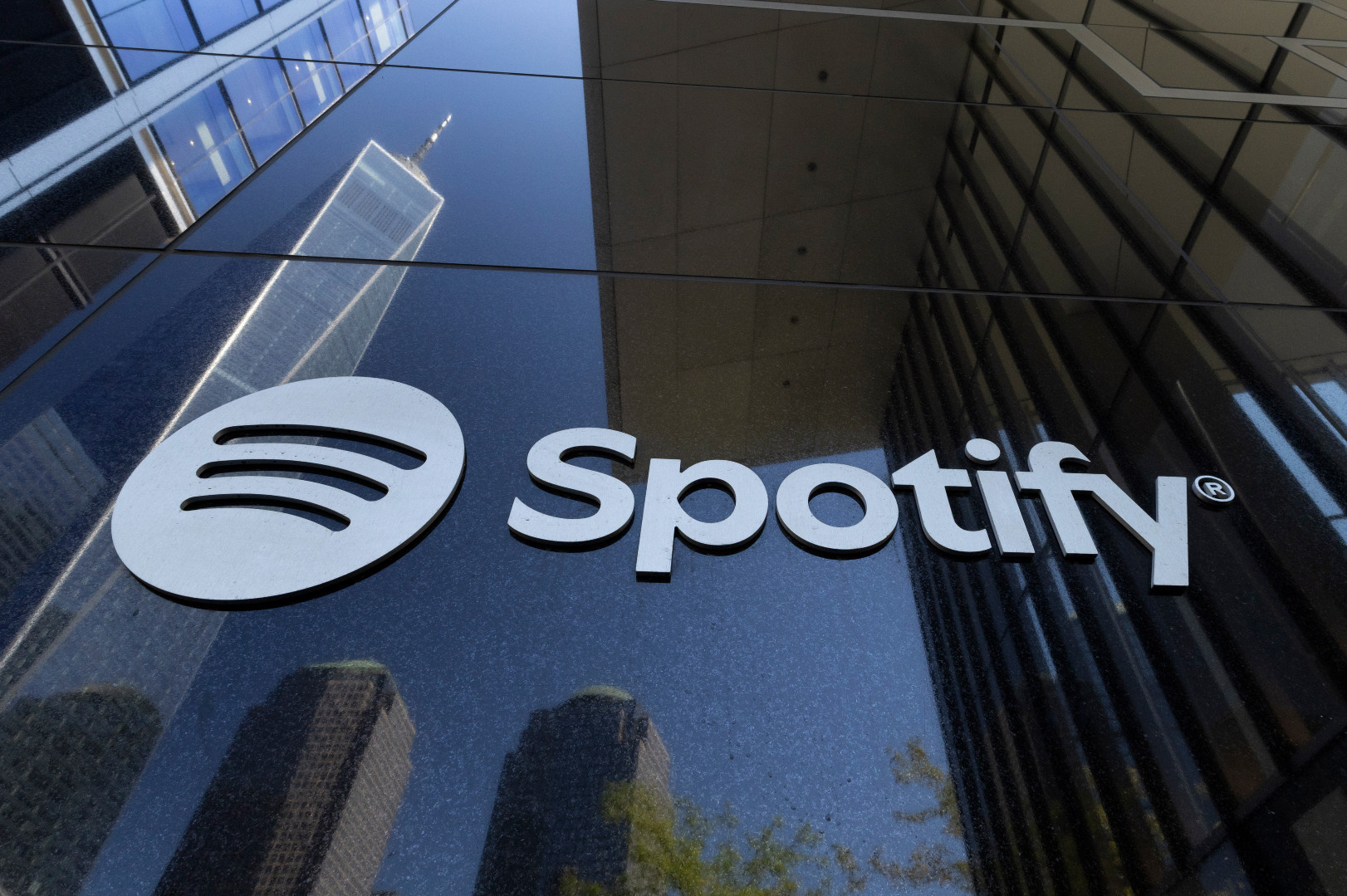 Spotify logo on a reflective building facade, with skyscrapers mirrored in the glass.