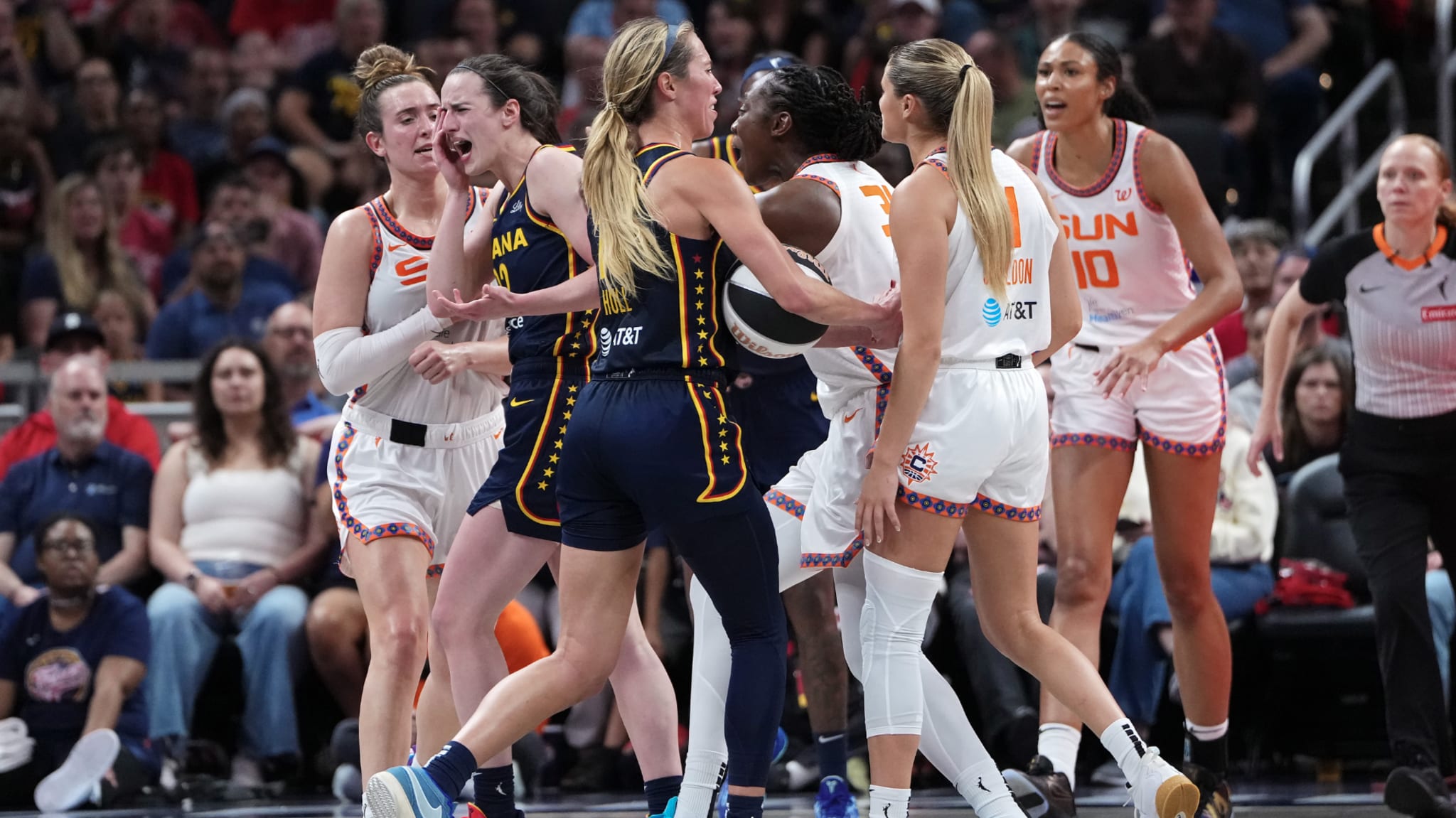 A group of WNBA players from Indiana Fever and Connecticut Sun during a game, engaged in a tense moment on the court.