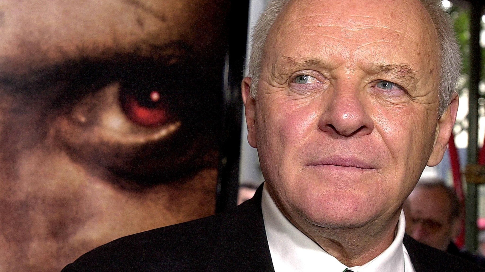 British-born actor Anthony Hopkins is interviewed next to a poster for his new film "Hannibal" in January 2001.