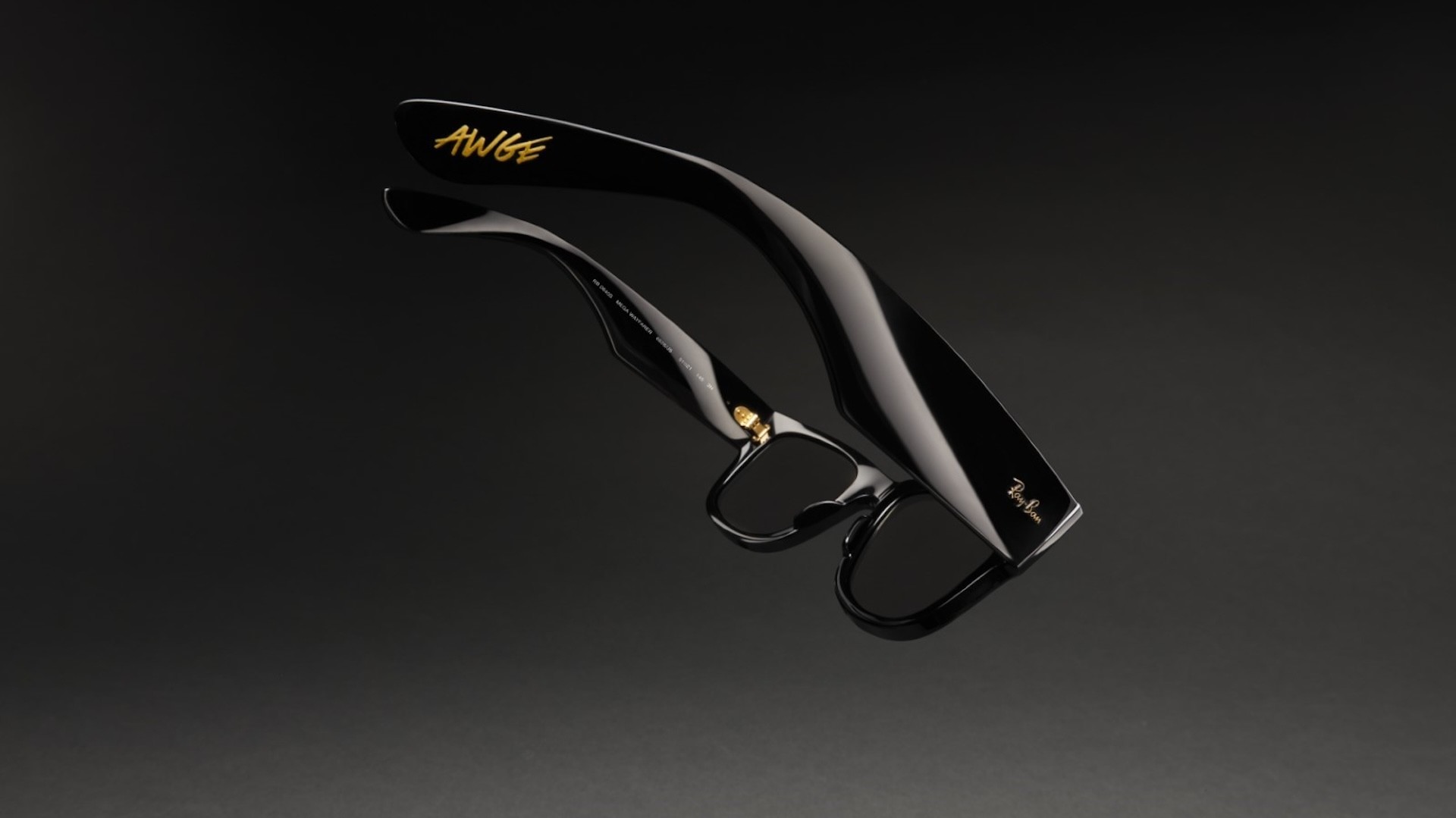Sleek black sunglasses with "AWGE" and "Ray-Ban" logos in gold on the arms, set against a dark background.