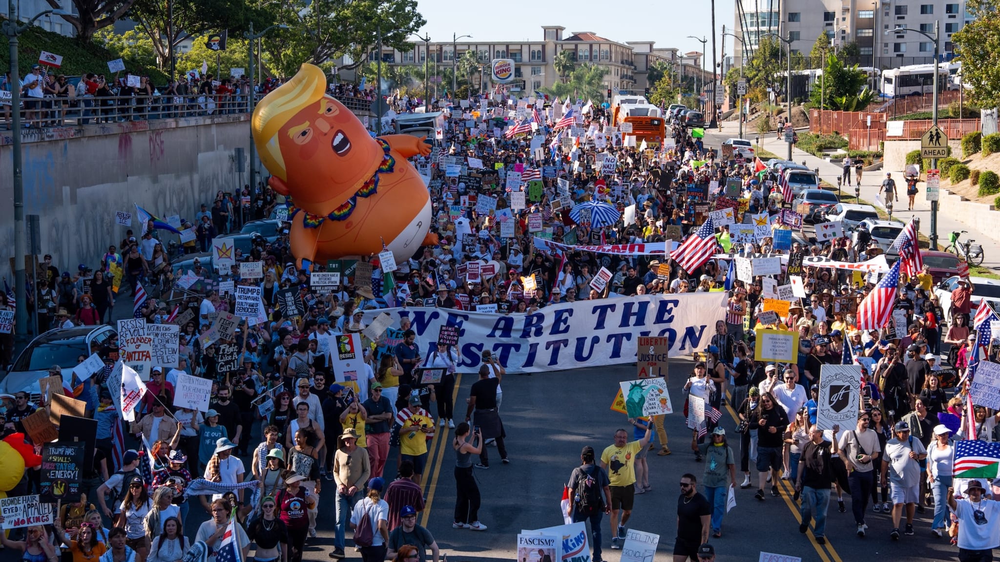 People hold signs and flags during a "No Kings" protest.