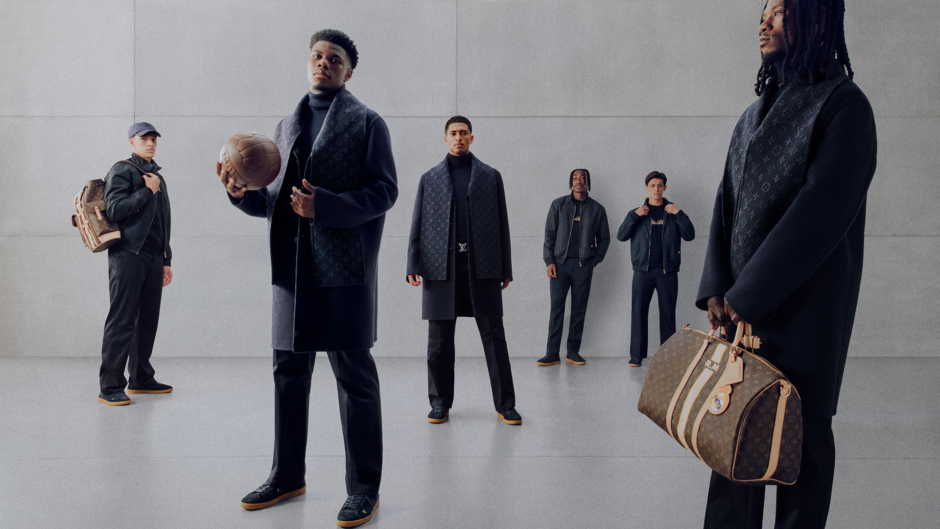 A group of men in stylish outfits pose in a minimalist setting. One holds a basketball, another a designer bag. Fashion-forward vibe.