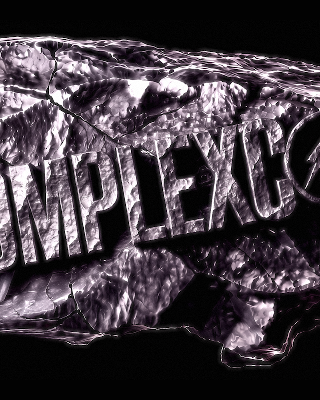 Text "COMPLEXCON" on a textured, metallic rock surface with a lightning bolt in the letter "O," set against a black background.