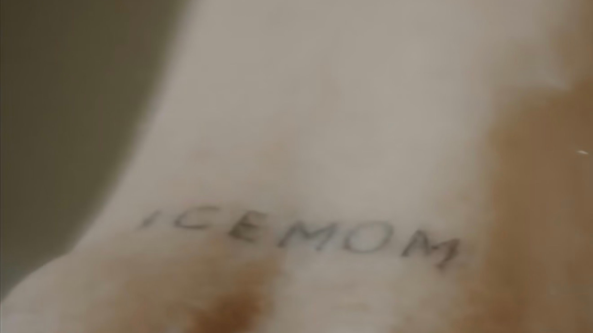 A tattoo on skin with the text "ICEMOM" in simple black lettering.