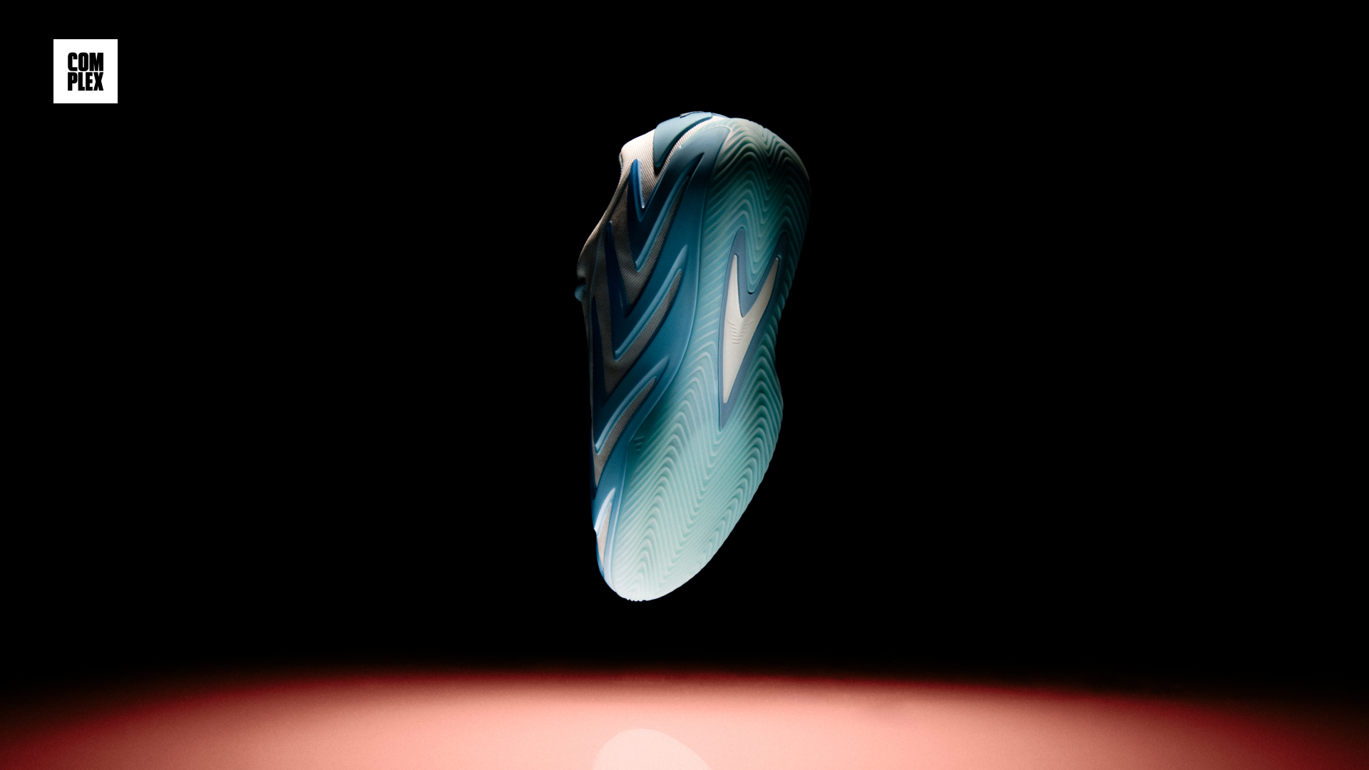 A sneaker with a futuristic design, featuring a blue and black color scheme, is illuminated against a dark background.