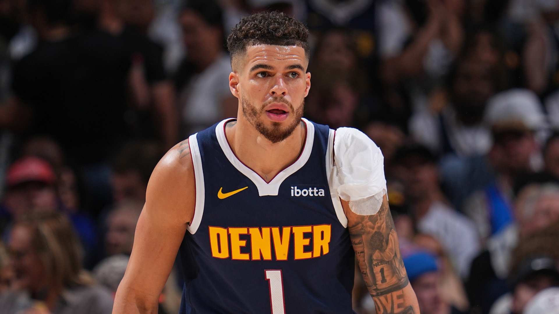 Michael Porter, Jr. in a Denver Nuggets jersey with number 1, on the court with a bandaged shoulder, focused expression.