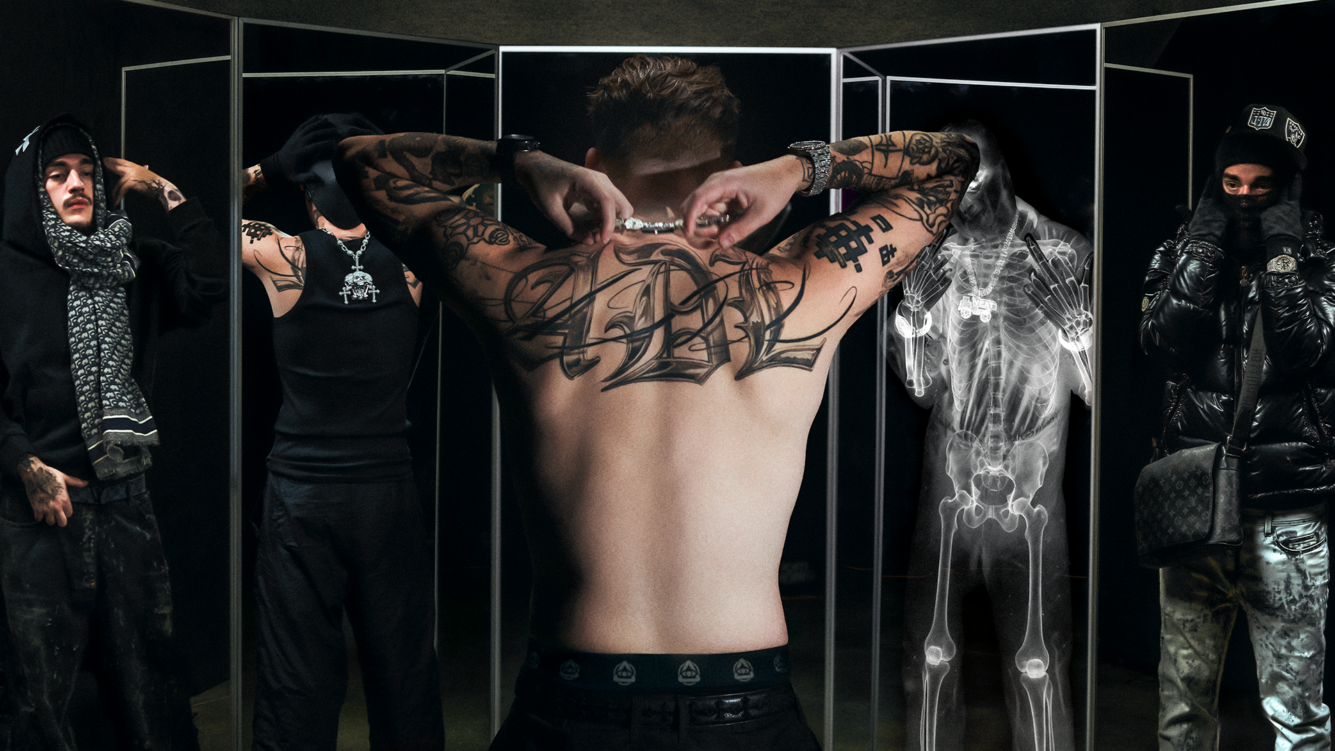 A shirtless man with tattoos stands in front of mirrors, surrounded by three men in streetwear and an X-ray reflection.