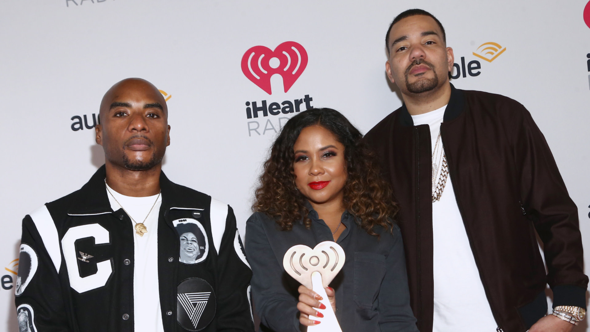 Charlamagne tha God, Angela Yee, and DJ Envy at an iHeartRadio event, posing with an award.