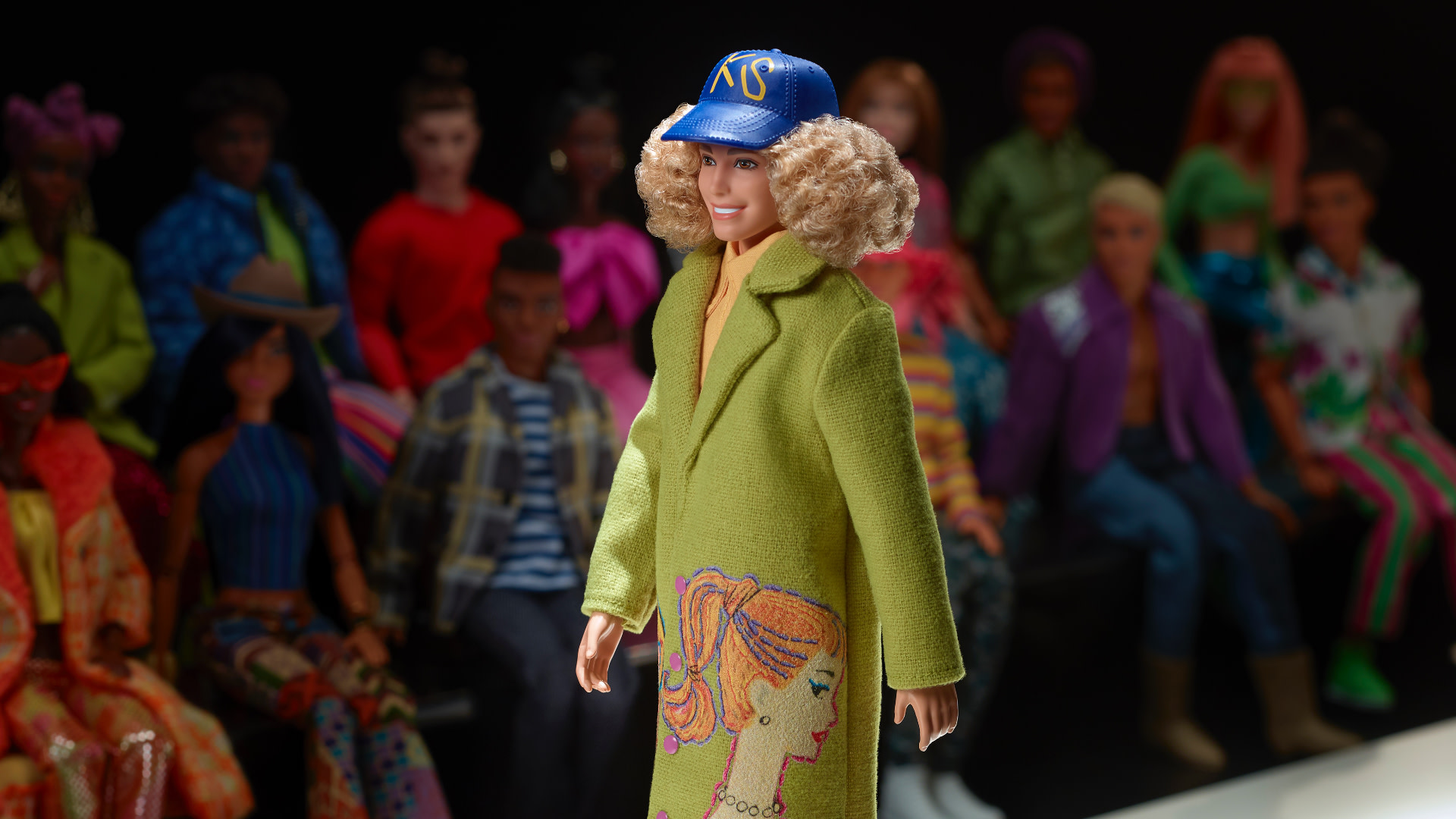 A Barbie doll on a runway, wearing a green coat and blue cap, surrounded by an audience of diverse dolls in colorful outfits.