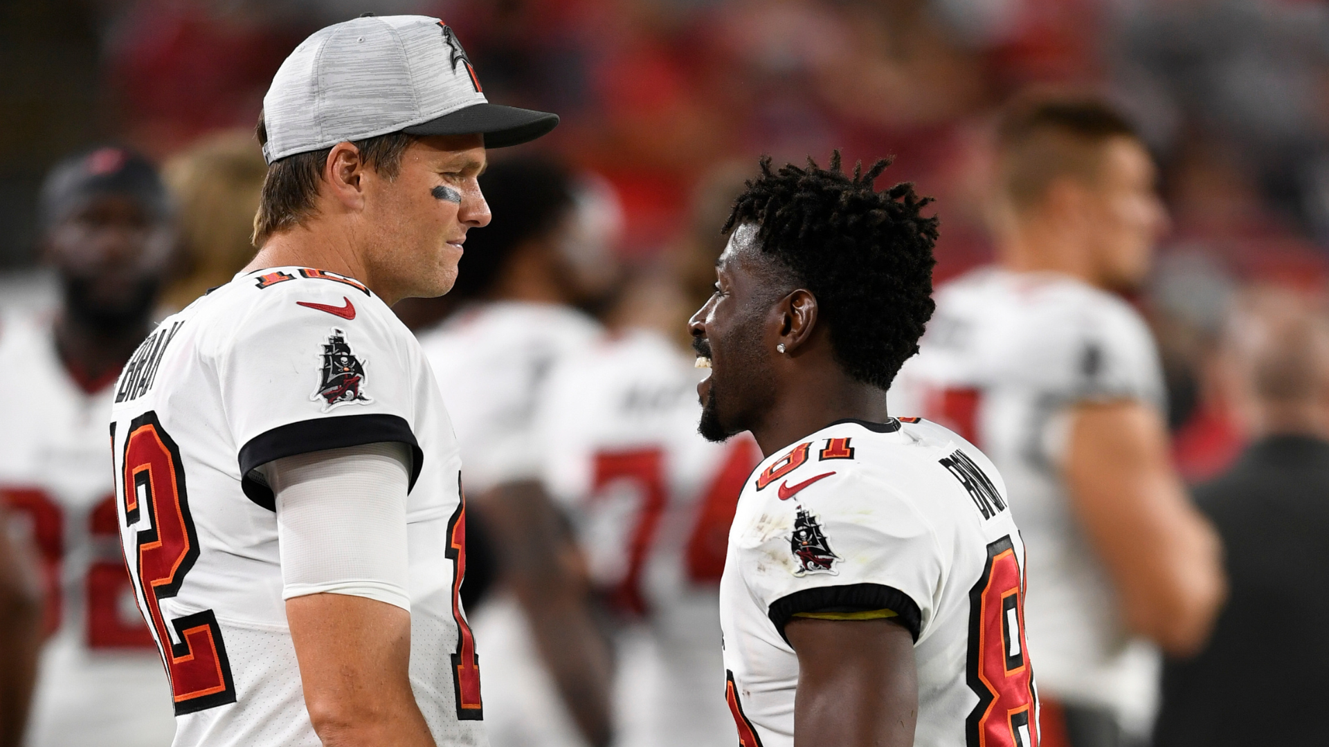 Tom Brady and Antonio Brown in Tampa Bay Buccaneers uniforms, talking on the sidelines during a game.