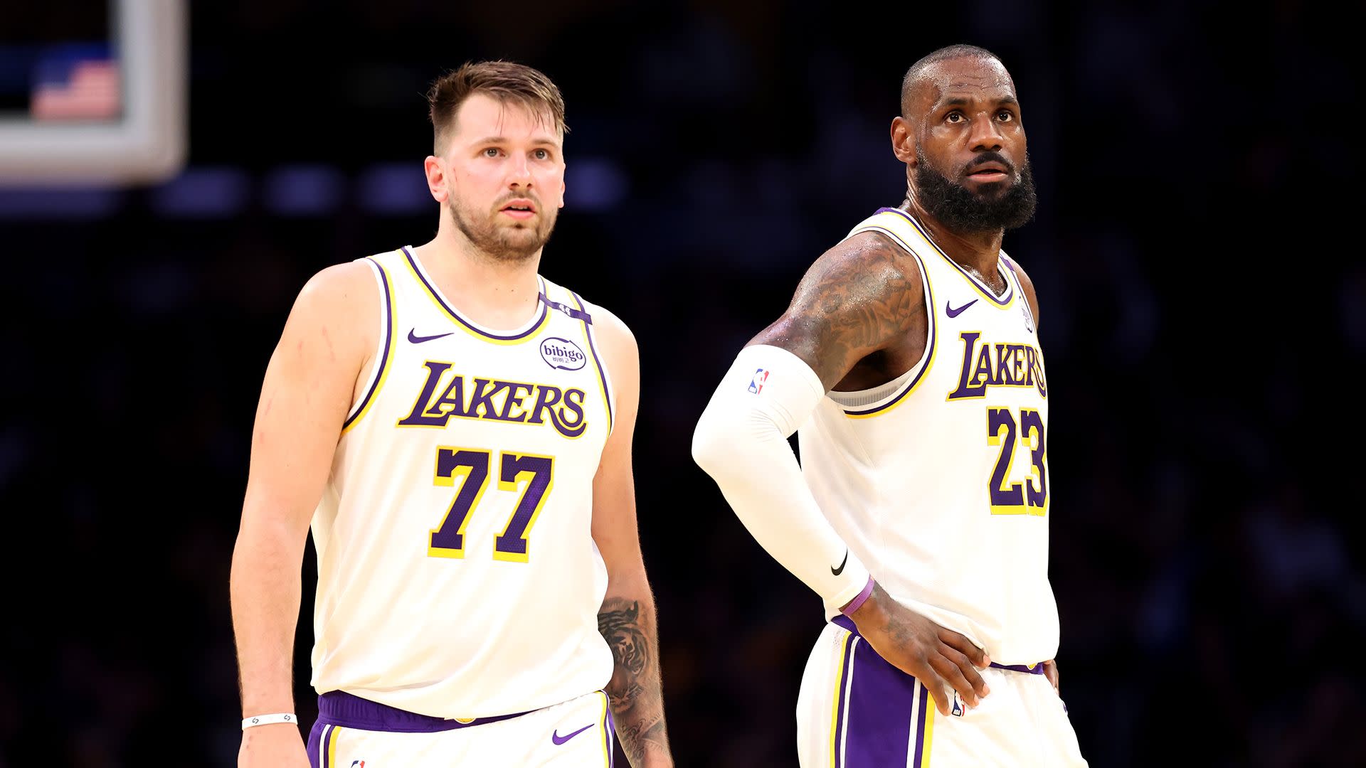 Luka Dončić and LeBron James in Lakers jerseys on a basketball court, focused and ready.