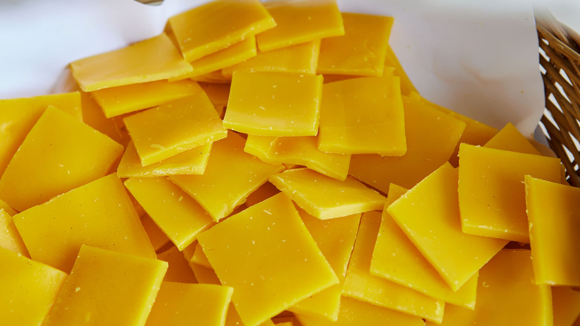 A pile of yellow square cheese slices stacked on a surface.