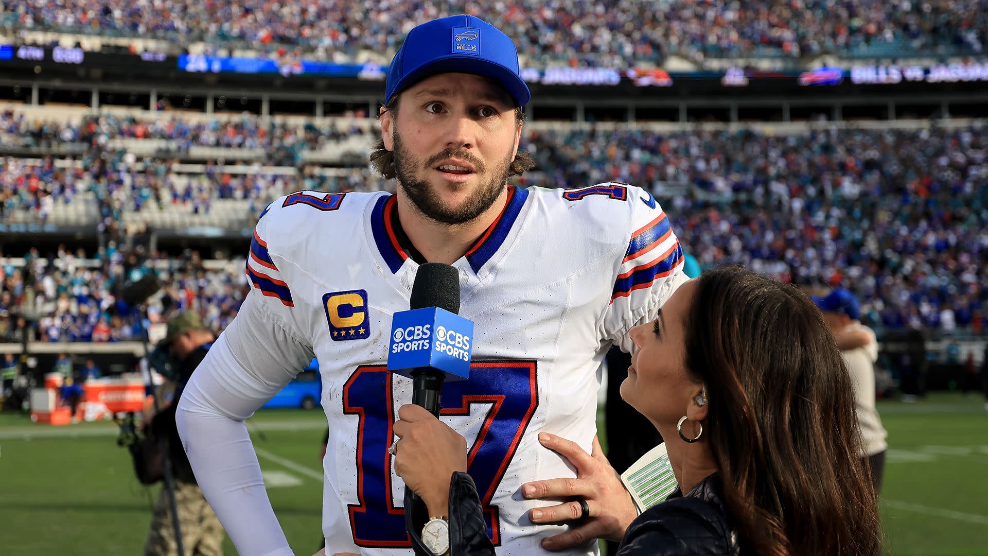 A football player in a Buffalo Bills uniform is being interviewed on the field by a CBS Sports reporter. The stadium is crowded.
