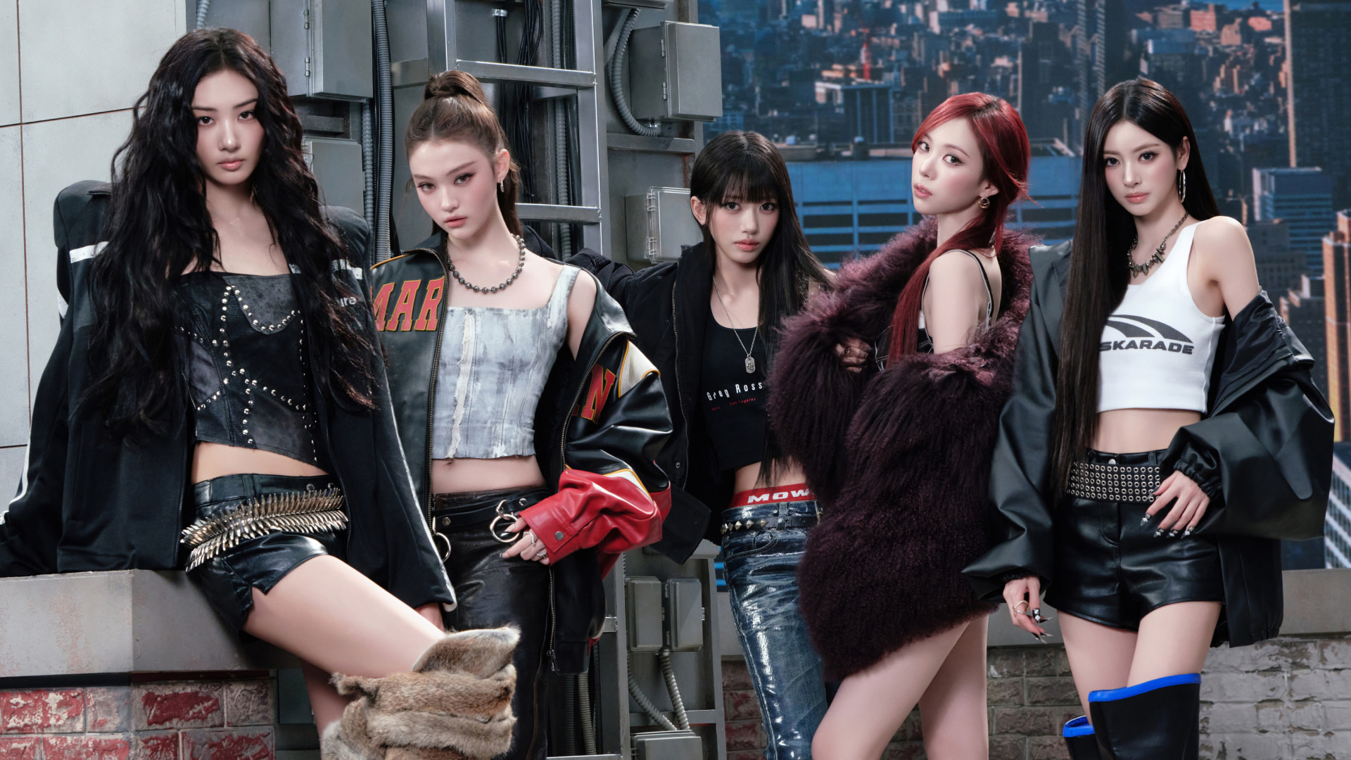 The five members of MEOVV in stylish urban outfits pose confidently on a rooftop, with a cityscape in the background.