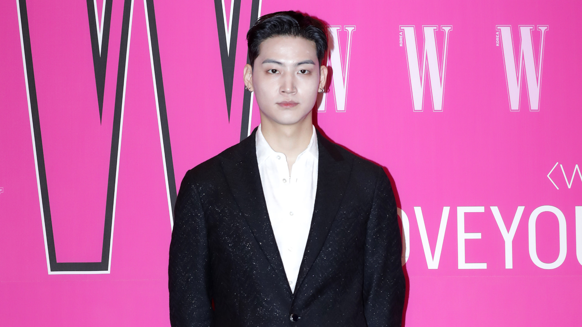 GOT7's Jay B in a black suit stands against a bright pink background with "W" logos.
