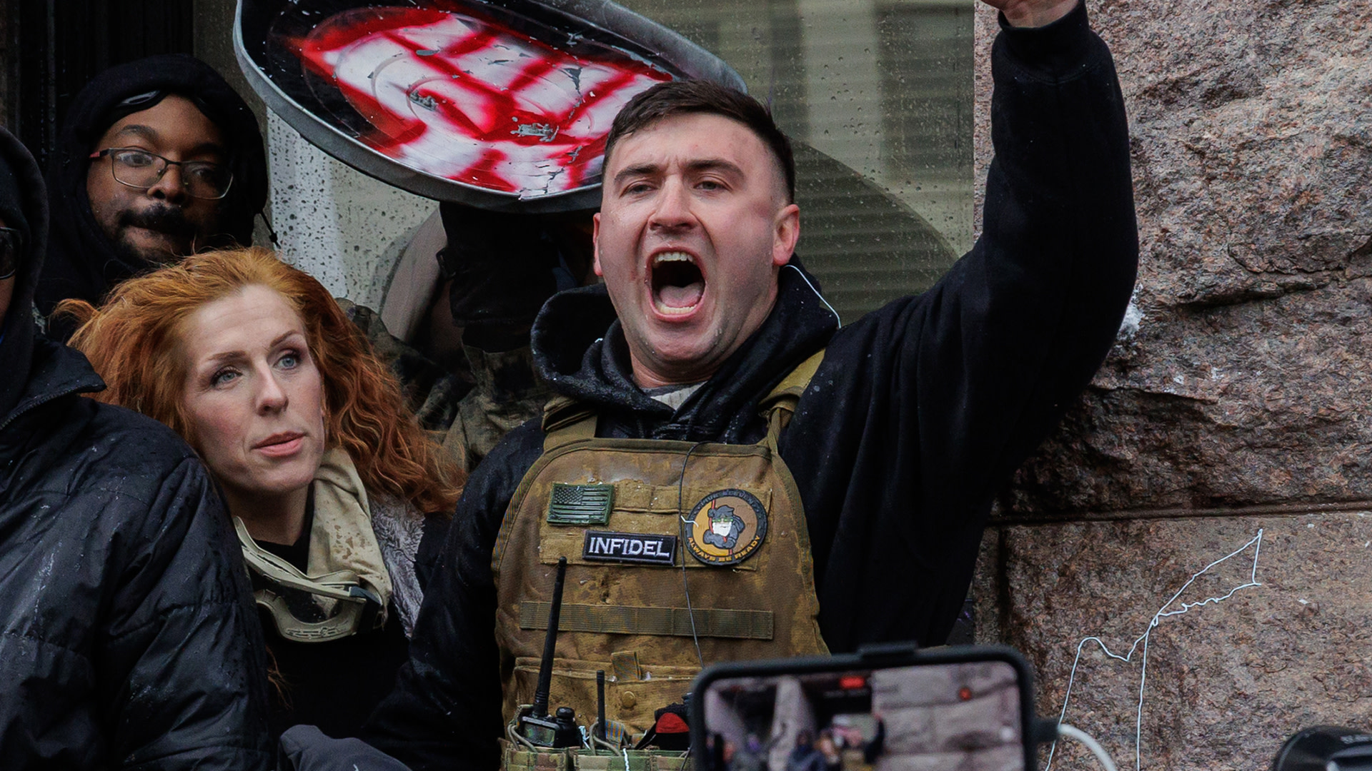 Jake Lang, a January 6 Capitol riot defendant who was recently pardoned by U.S. President Donald Trump, gestures while standing on a window ledge of City Hall during a self-organized anti-Muslim and pro-ICE demonstration in Minneapolis, Minnesota.
