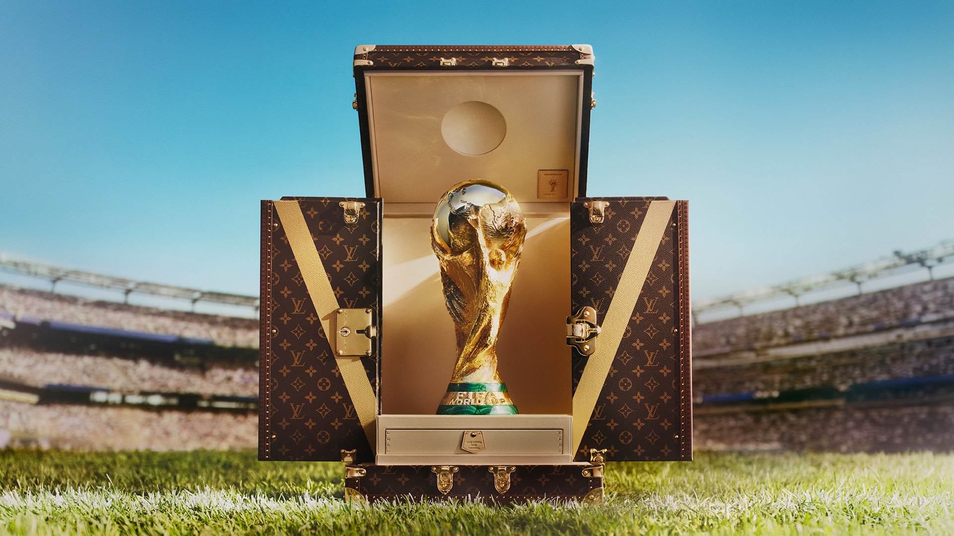 The FIFA World Cup trophy in a Louis Vuitton case on a soccer field.