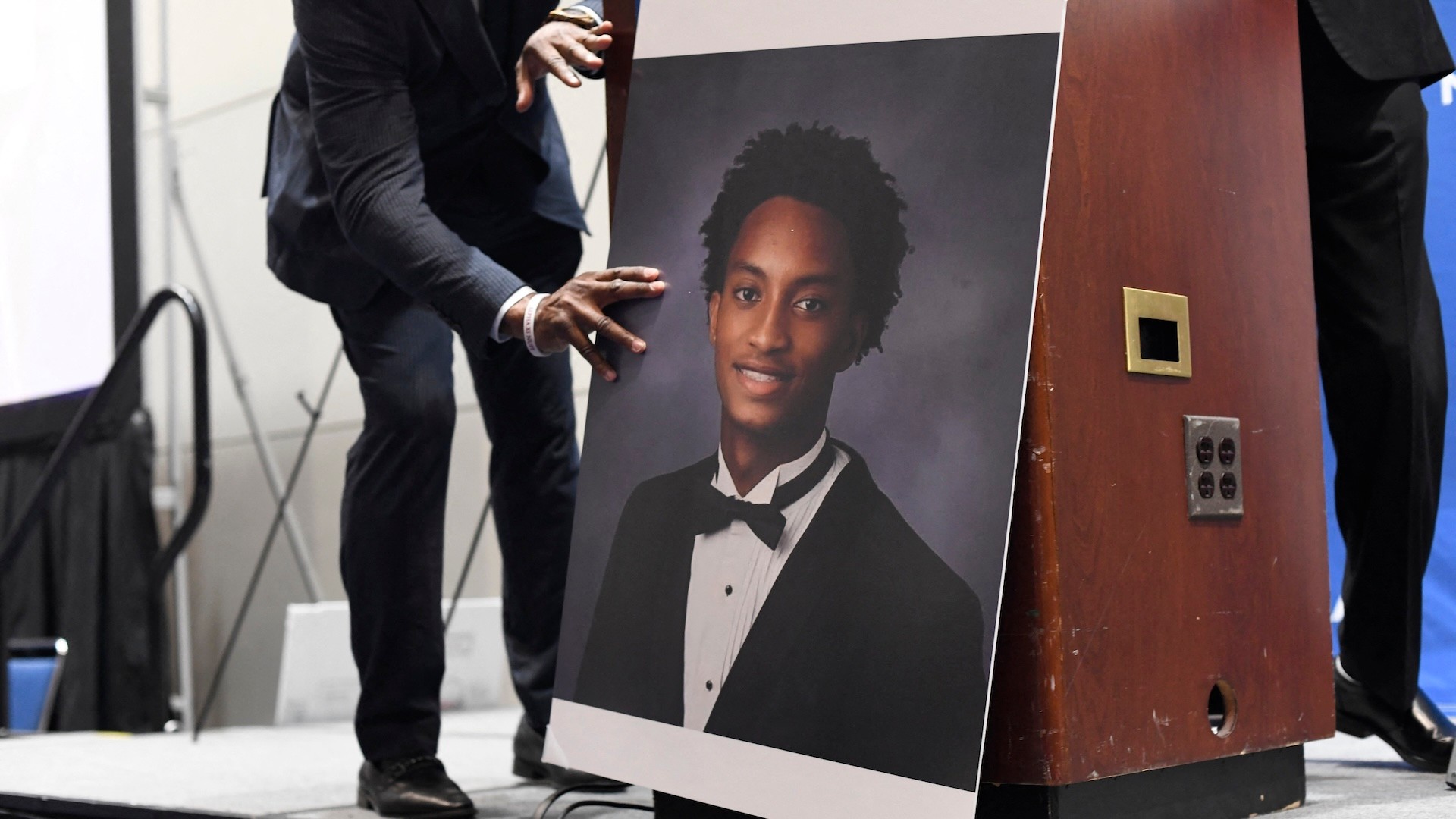 A man places a photograph of Nolan Xavier Wells in front of the podium before a news conference during the 117th NAACP National Convention at McCormick Place in Chicago, Illinois, on July 22, 2026.