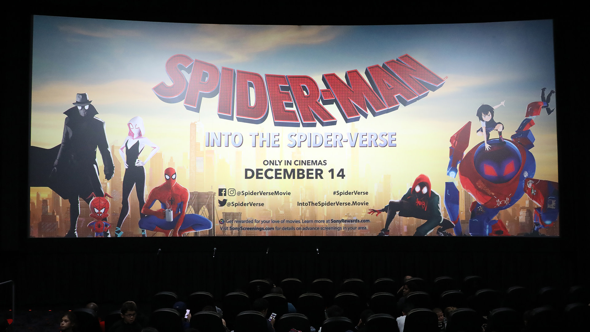 Movie theater screen showing "Spider-Man: Into the Spider-Verse" poster with various Spider-Man characters, release date December 14.