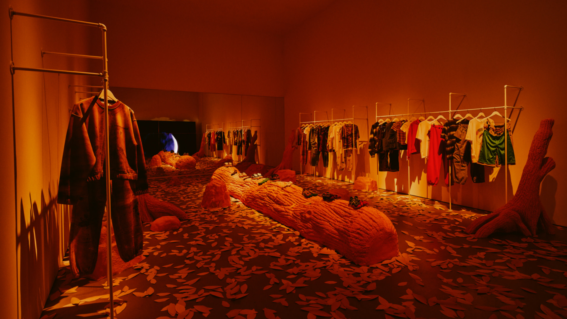 A clothing store with racks of colorful garments, tree-like sculptures, and a patterned floor, lit with warm, ambient lighting.