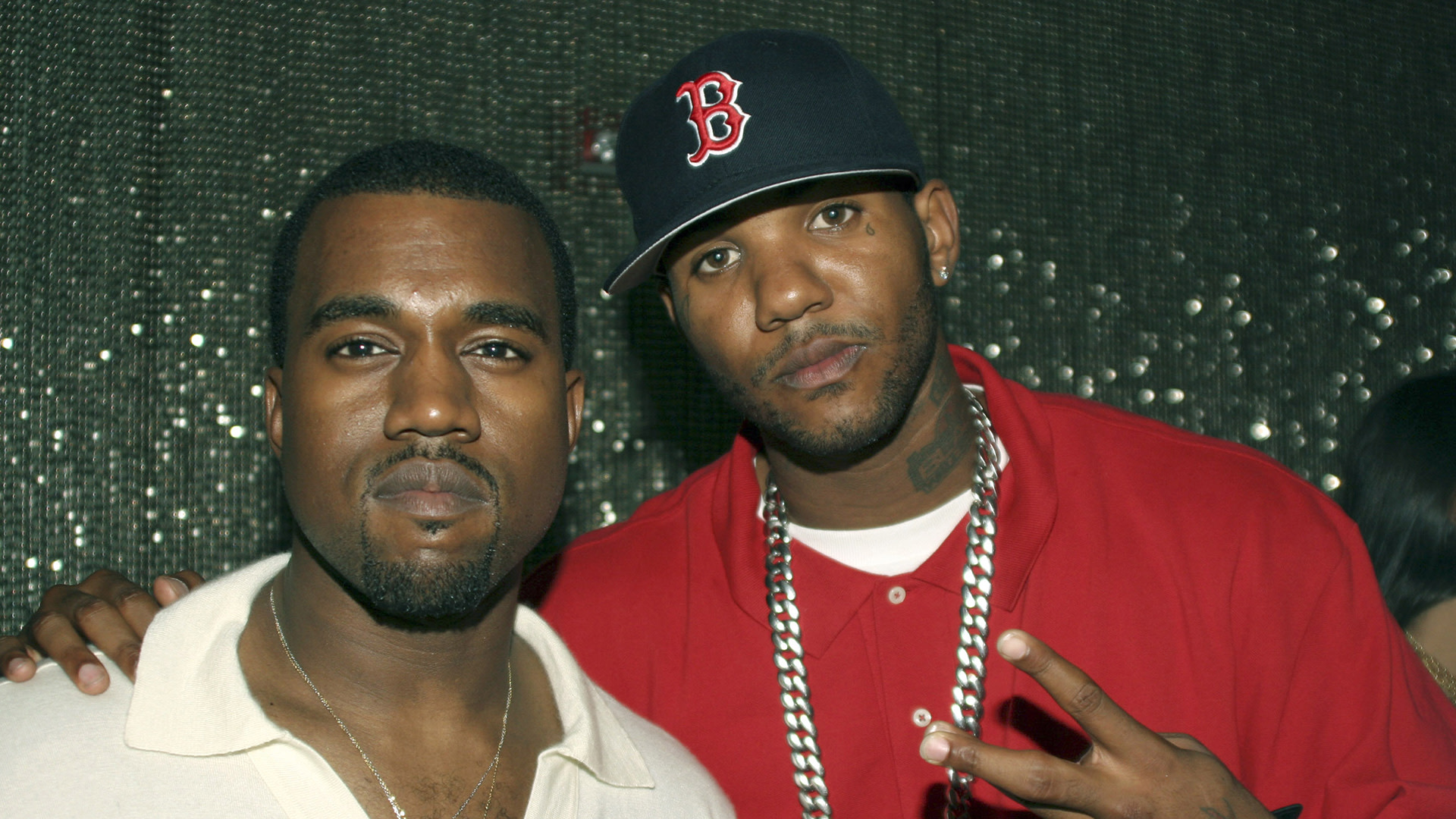 Kanye West and The Game posing together. Kanye is wearing a light-colored shirt, and The Game is in a red shirt and Boston cap.