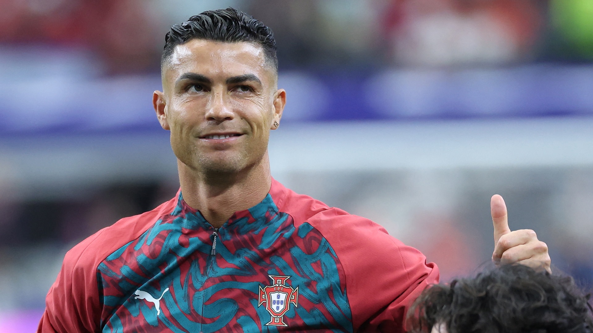 Cristiano Ronaldo in a Portugal jersey, smiling and giving a thumbs-up gesture.