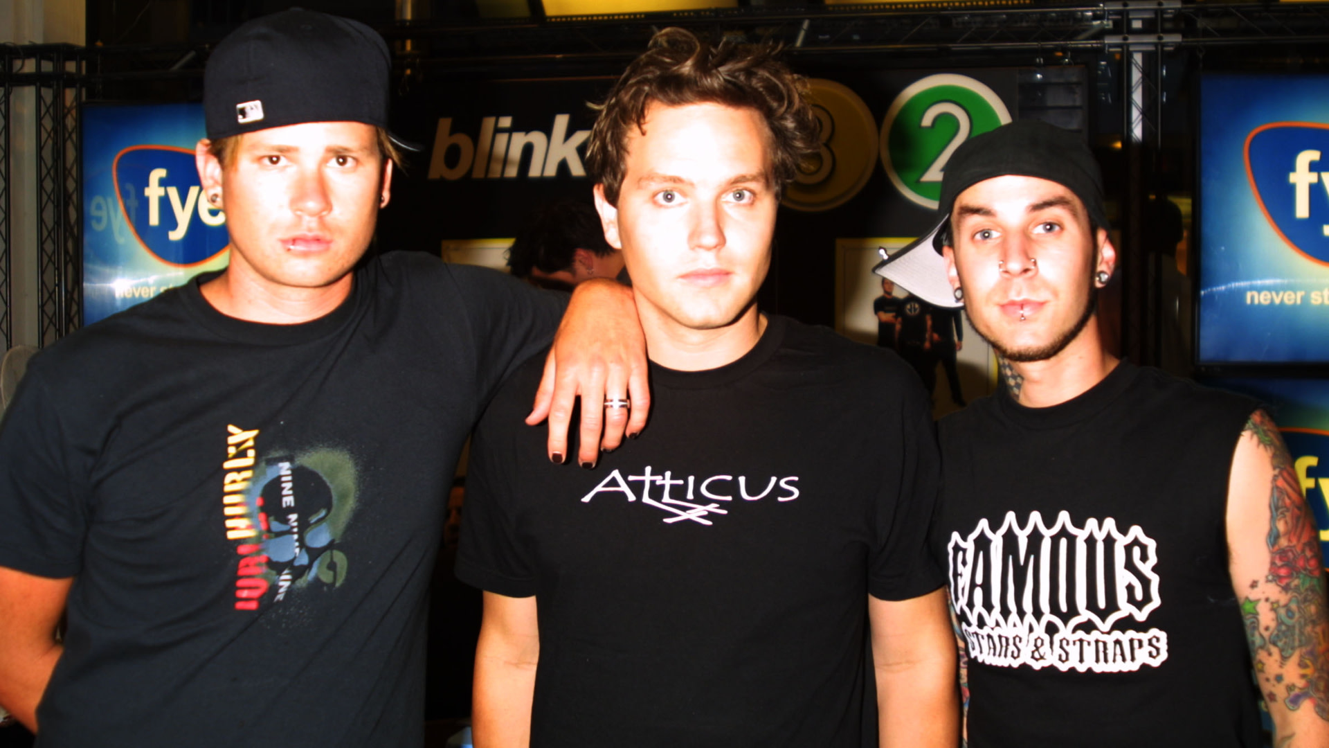 Members of Blink-182, Tom DeLonge, Mark Hoppus, and Travis Barker, pose together in casual attire at an event.