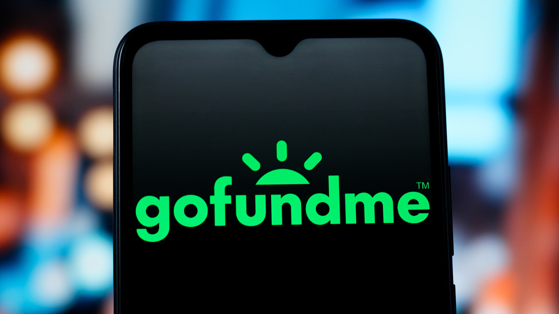 A smartphone screen displaying the GoFundMe logo in green against a blurred background.