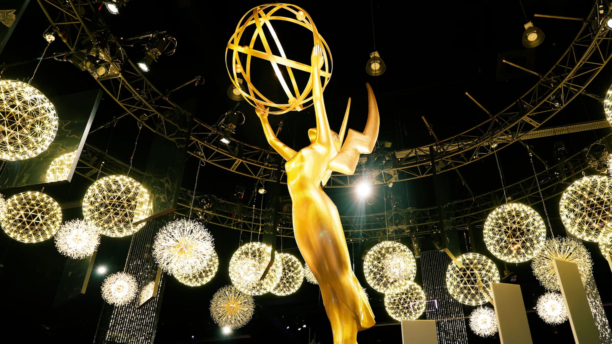 A large, golden Emmy Award statue surrounded by decorative glowing lights, set against a dark background.