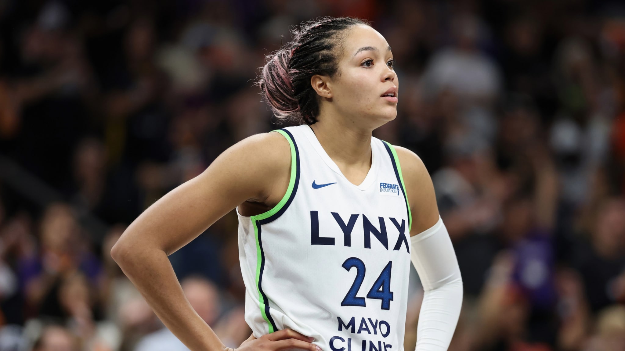 A basketball player wearing a Minnesota Lynx jersey with the number 24 stands on the court, hands on hips, during a game.