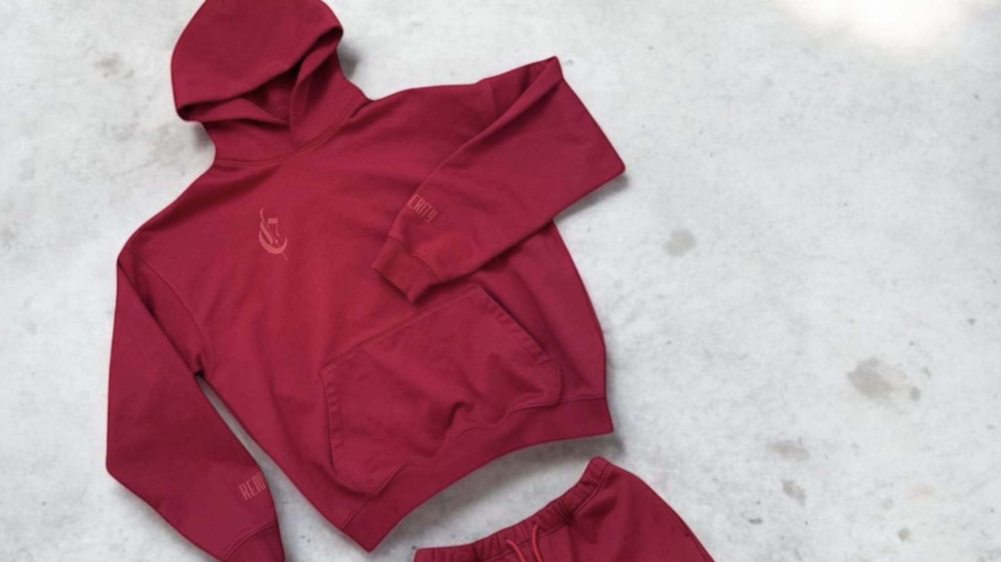 A red hoodie and matching shorts set laid on a light surface.