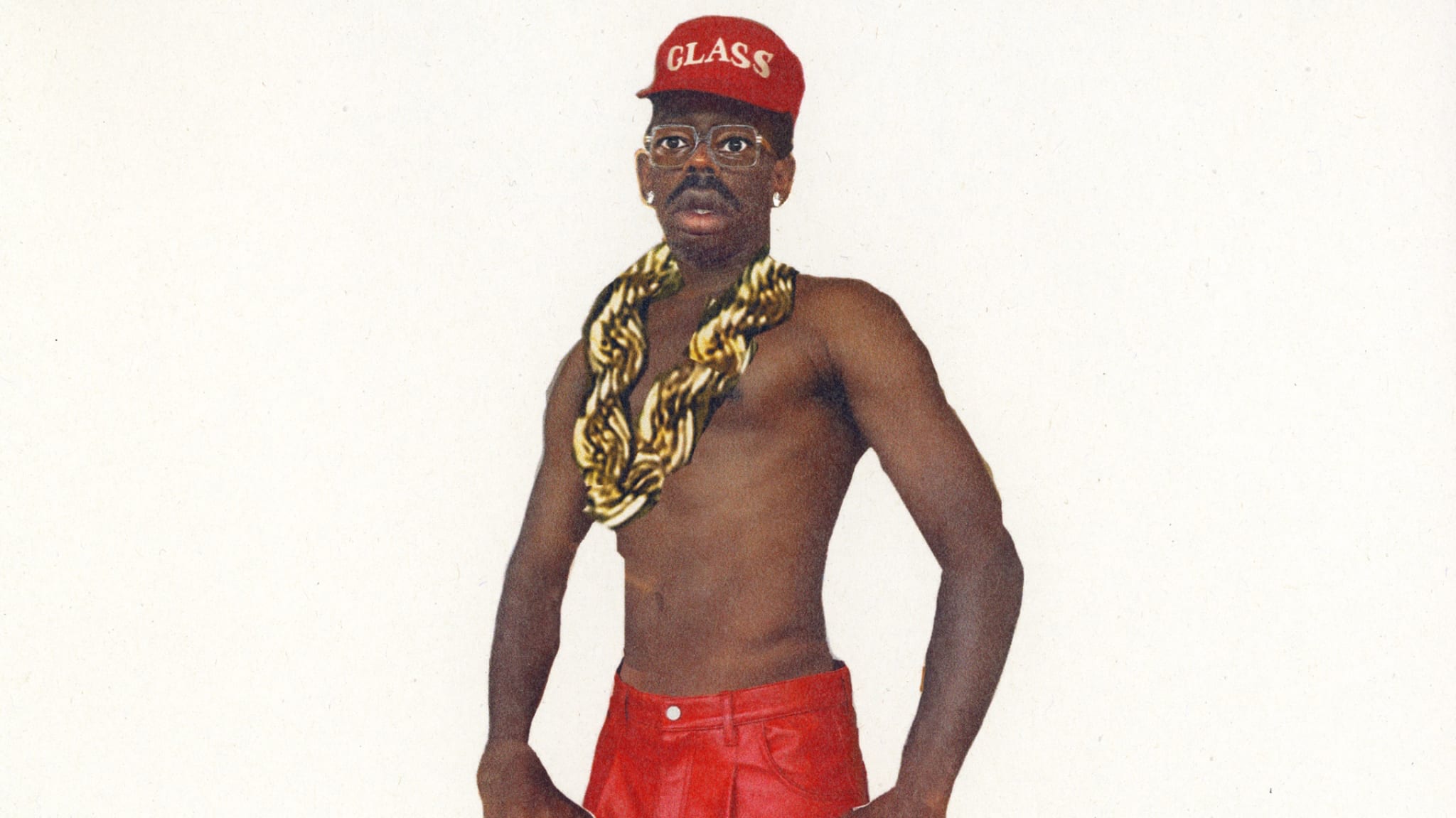 A shirtless Tyler wearing red pants, a red cap that says "GLASS," glasses, and a large gold chain necklace, poses confidently.