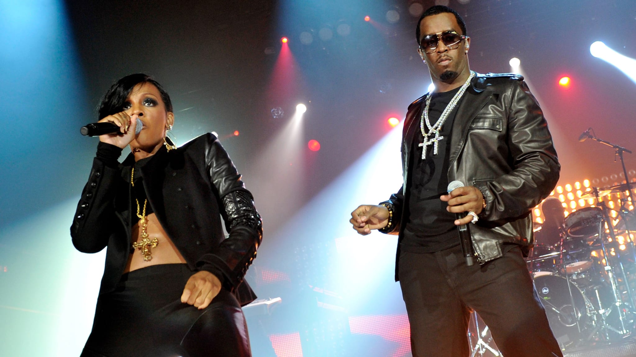 Singer Dawn Richard and rapper Diddy performing on stage, both in black outfits, with microphones, in a concert setting.