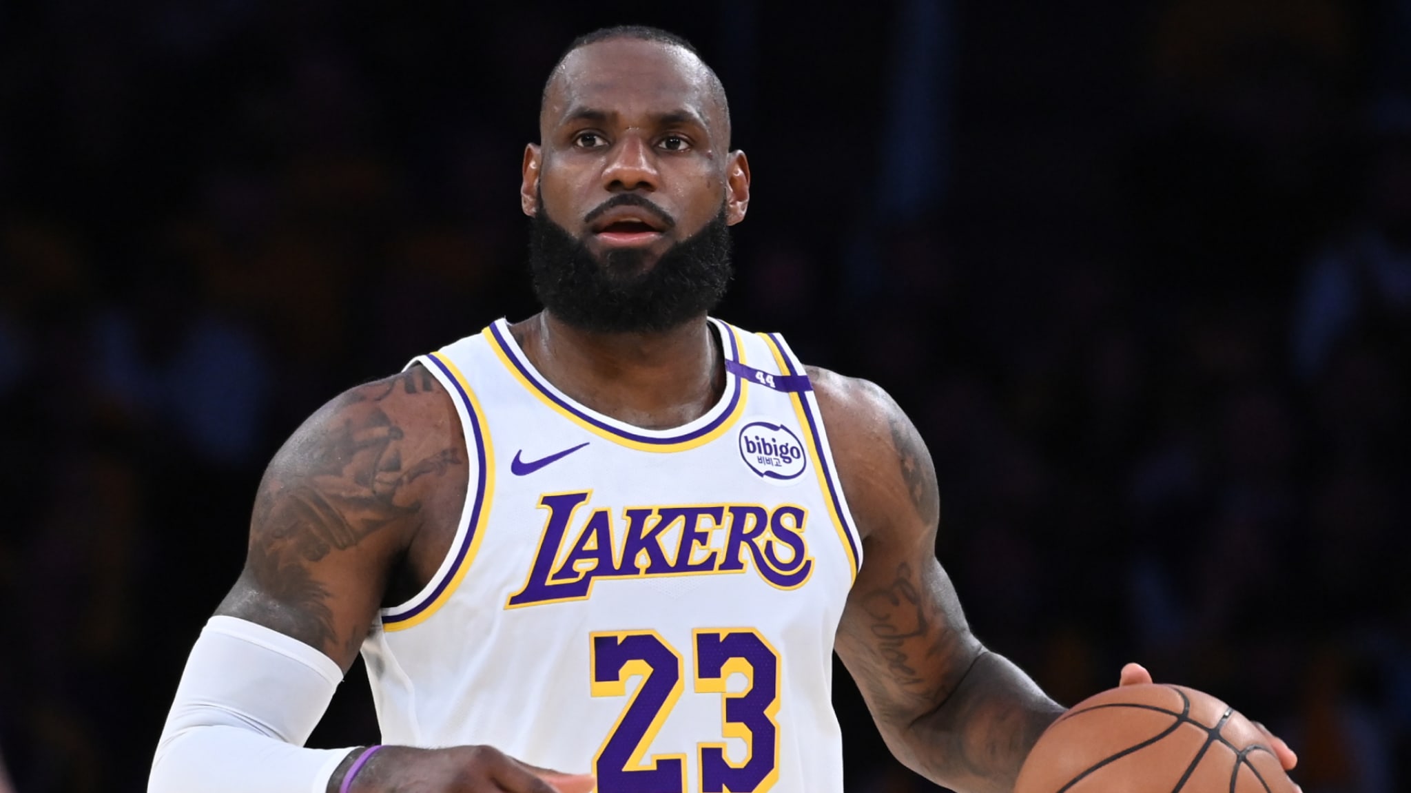 LeBron James in a Lakers jersey, holding a basketball during a game, focused and in action.