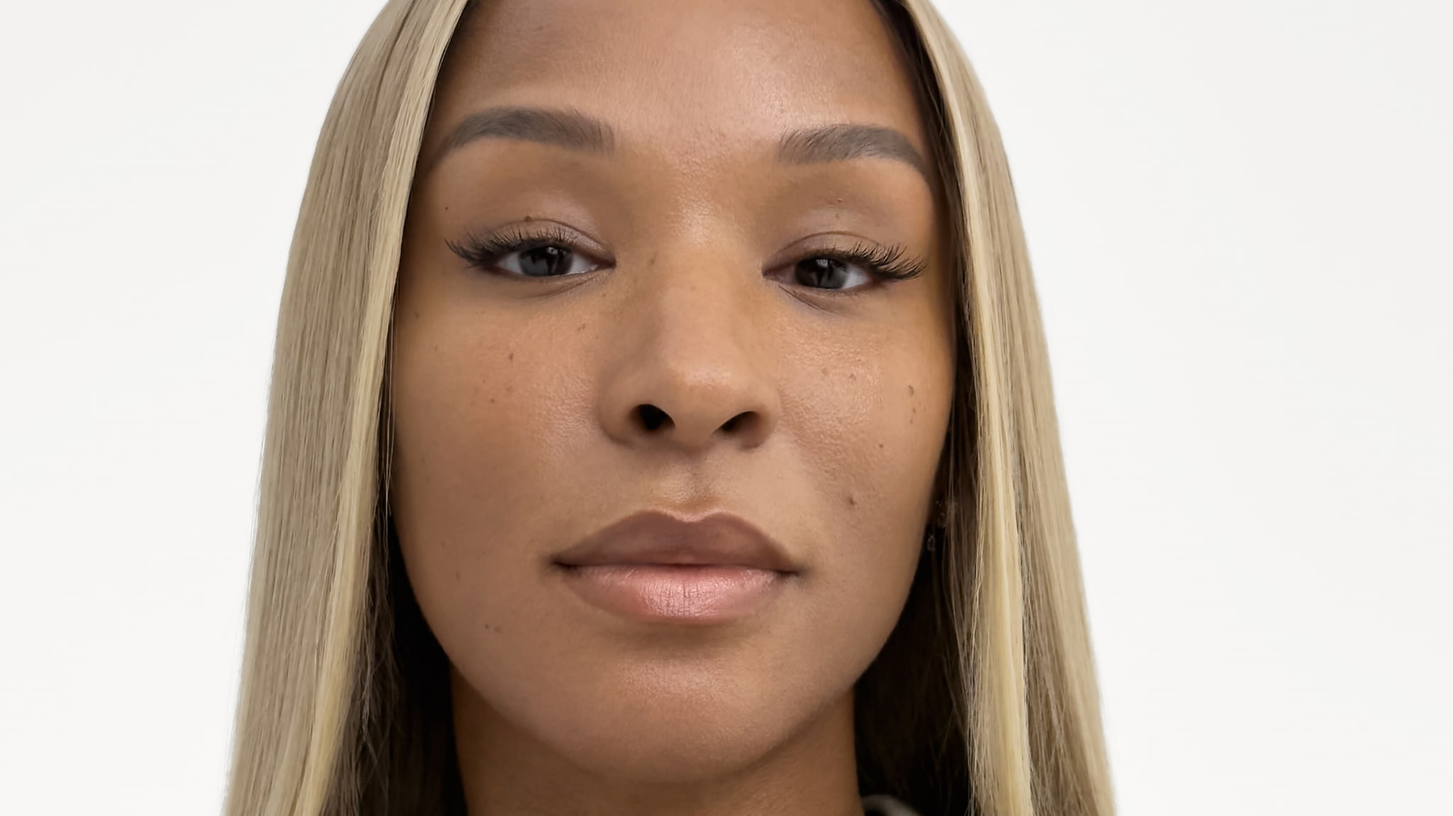 A woman with long, straight blonde hair and a neutral expression against a plain background.