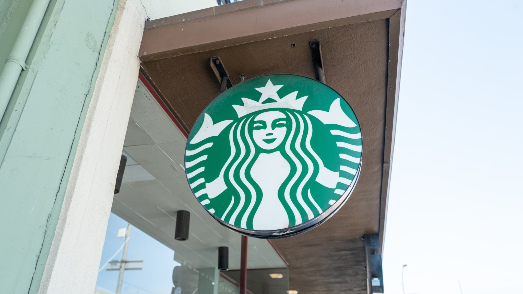 Starbucks logo sign with the iconic green siren, mounted on the exterior of a building.