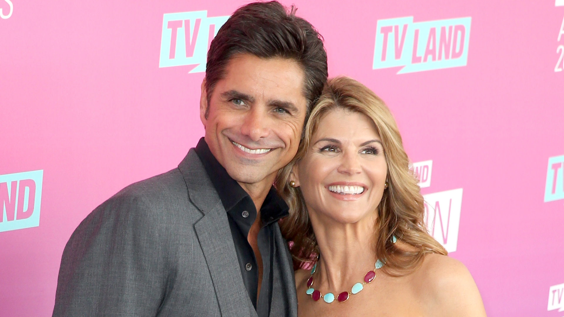 John Stamos and Lori Loughlin smiling on the red carpet at a TV Land event.