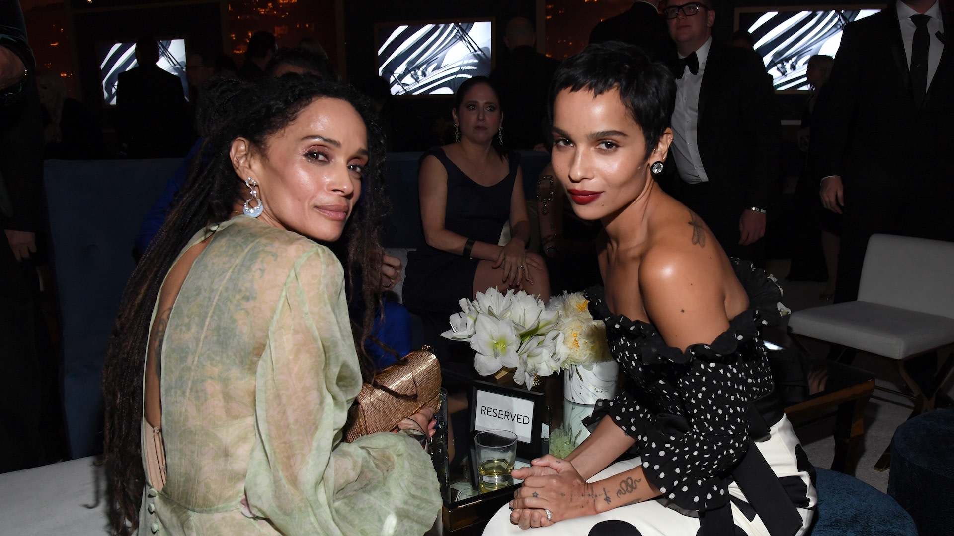 Lisa Bonet and Zoë Kravitz sitting together at an event, surrounded by other attendees.