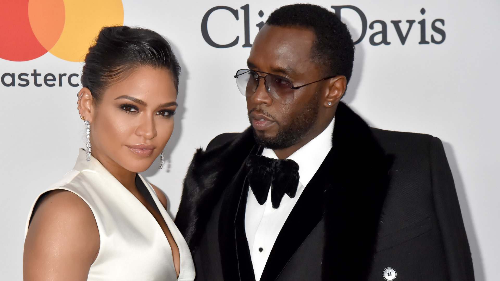 Cassie in a white dress and Sean "Diddy" Combs in a tuxedo at an event, posing together.