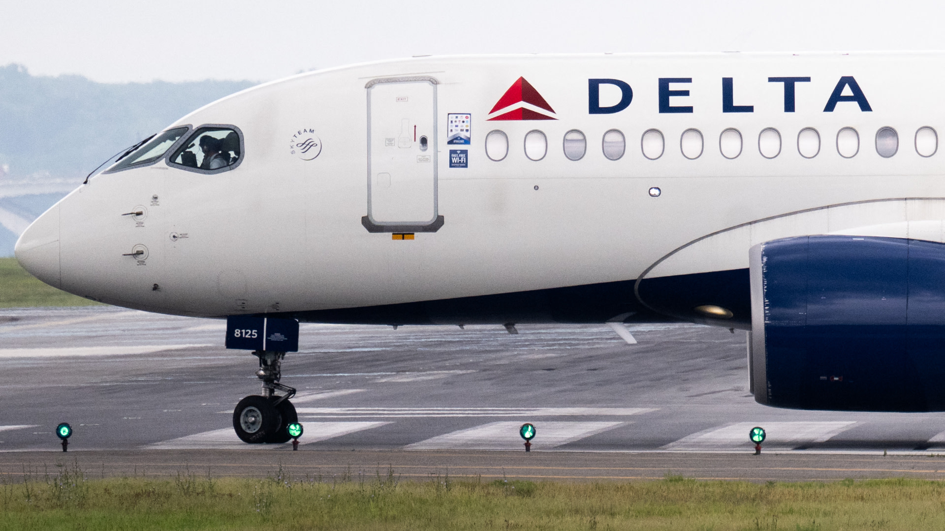 A Delta Air Lines aircraft on the runway, showing the front section with the logo and nose landing gear.