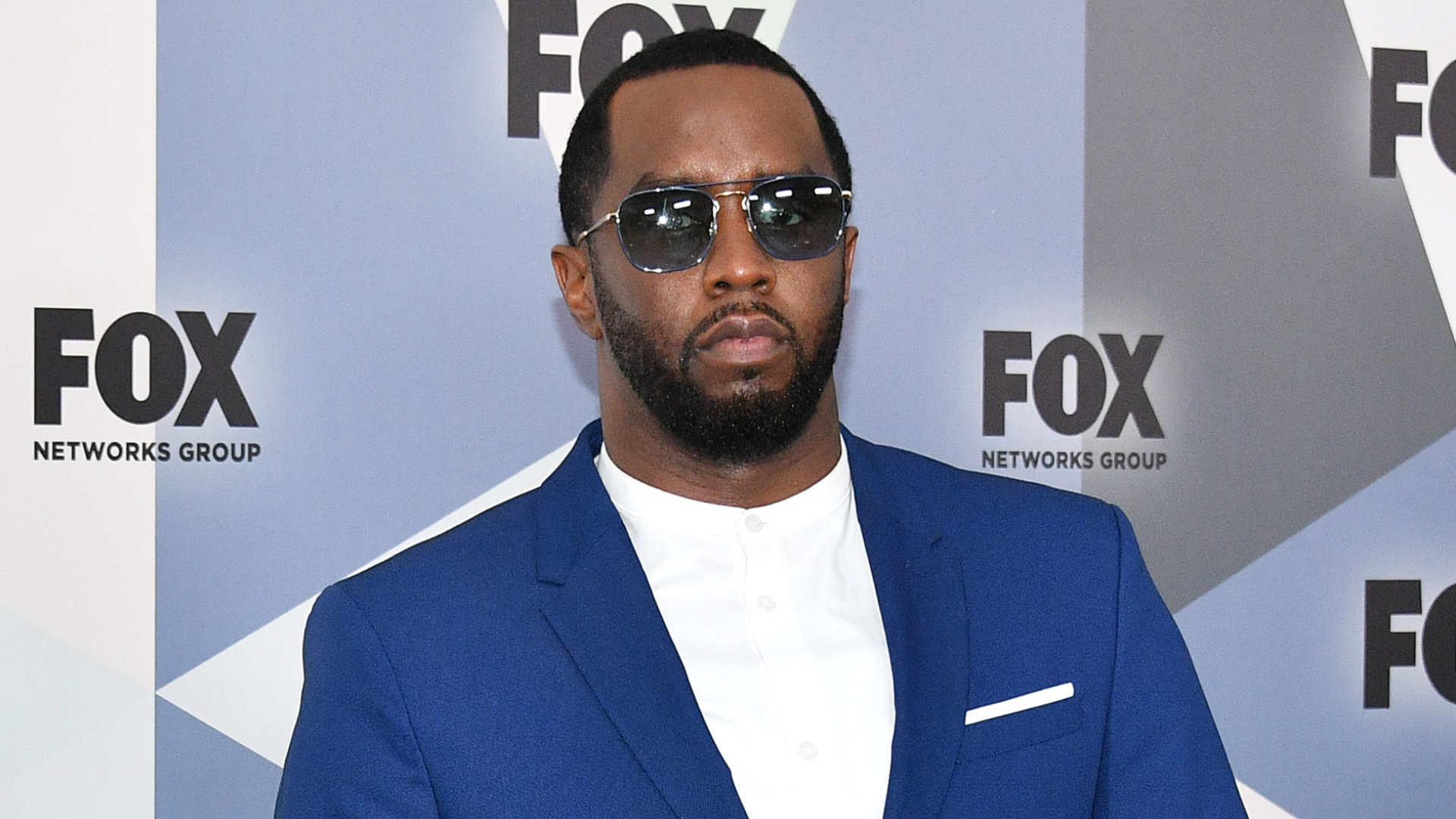 Sean Combs, also known as Diddy, in a blue suit and sunglasses, at a FOX event.