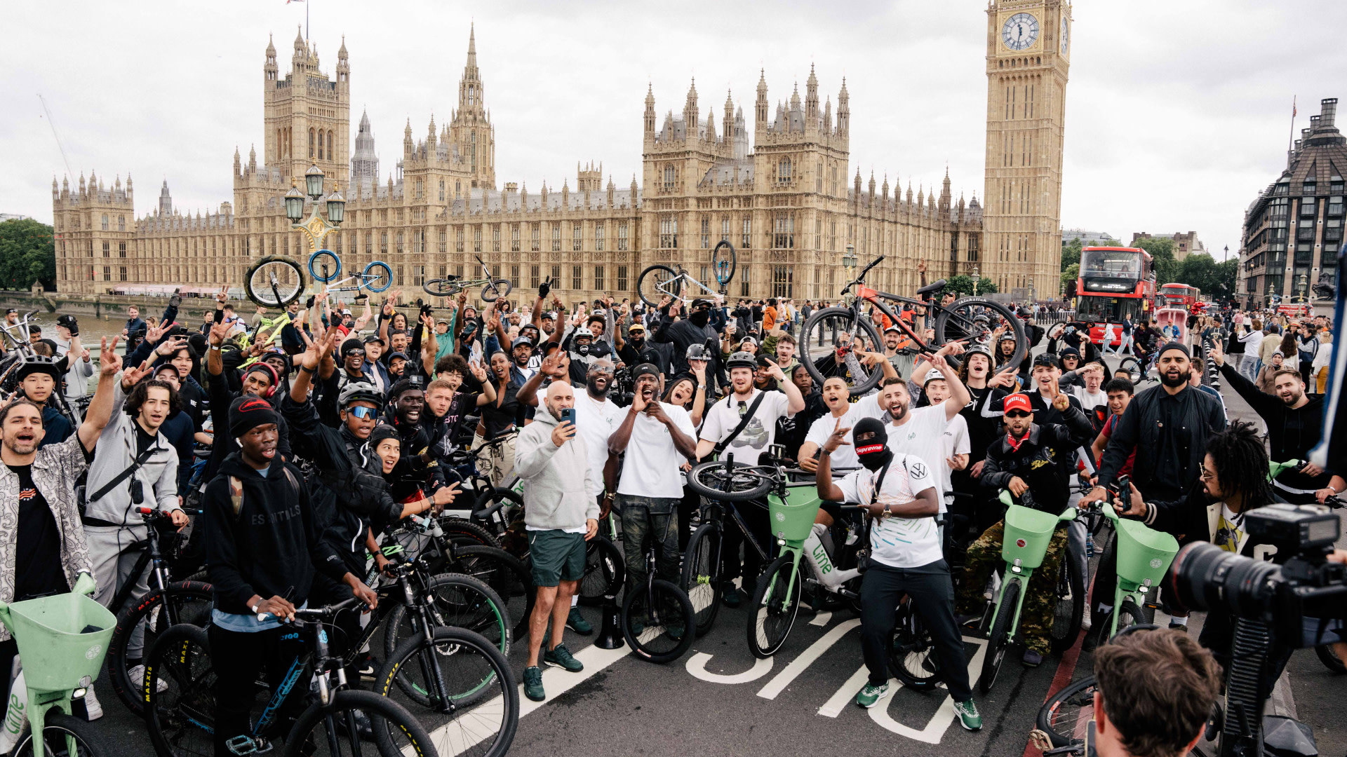 A large group of cyclists posing with their bikes in front of the Houses of Parliament and Big Ben in London.