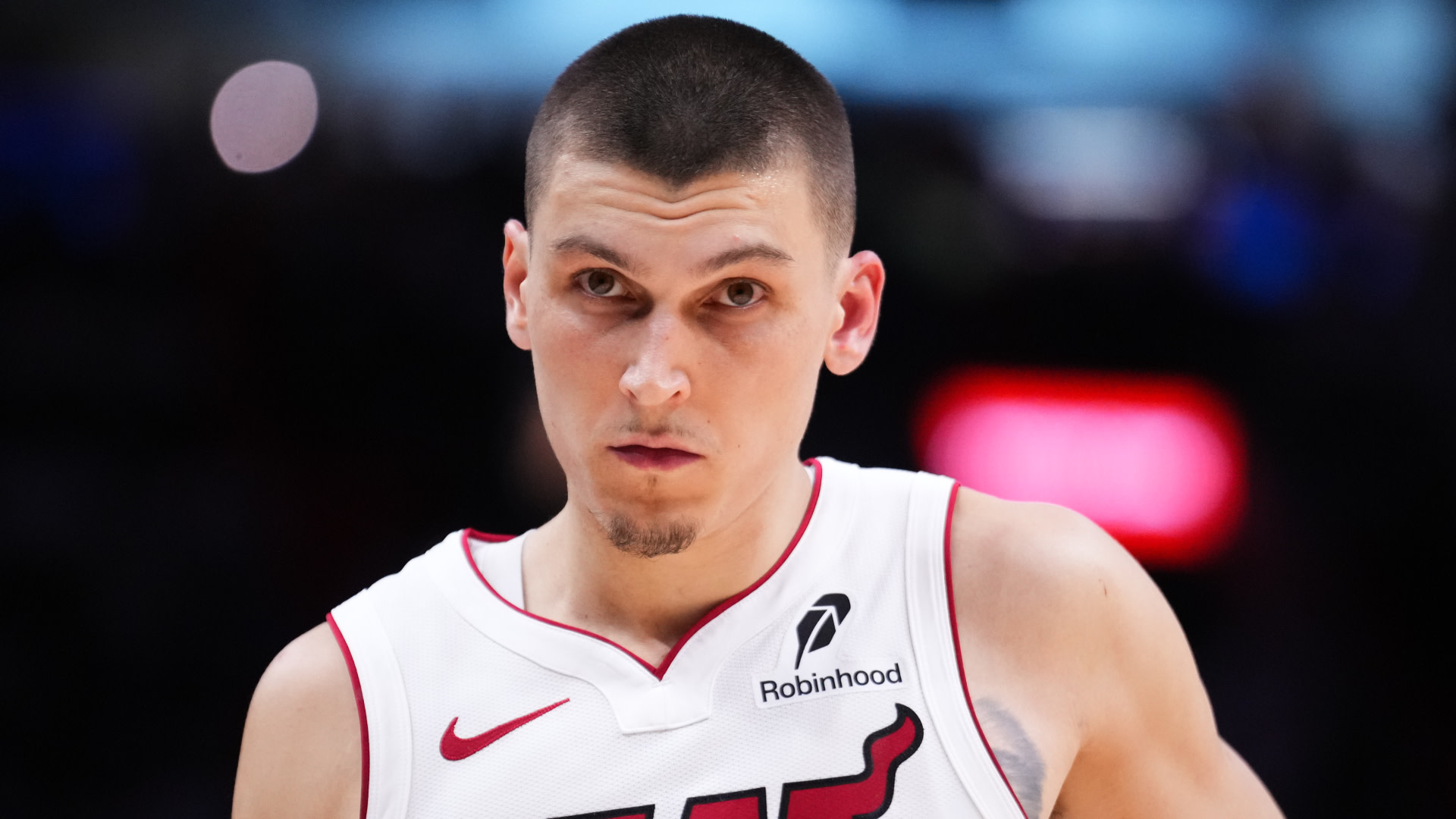 Tyler Herro in a Miami Heat jersey, focused, with a blurred background.