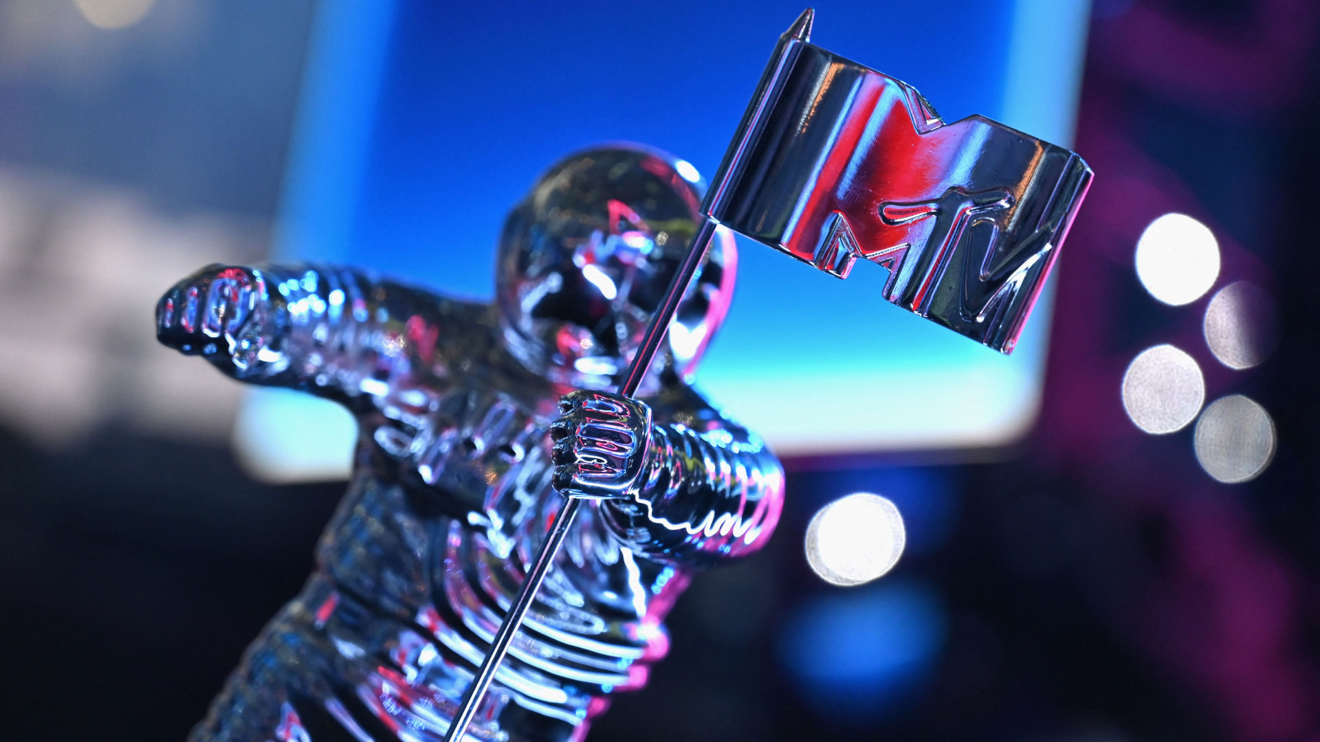 A close-up of the MTV Video Music Award trophy, featuring a silver astronaut holding an MTV flag, with a blurred background.