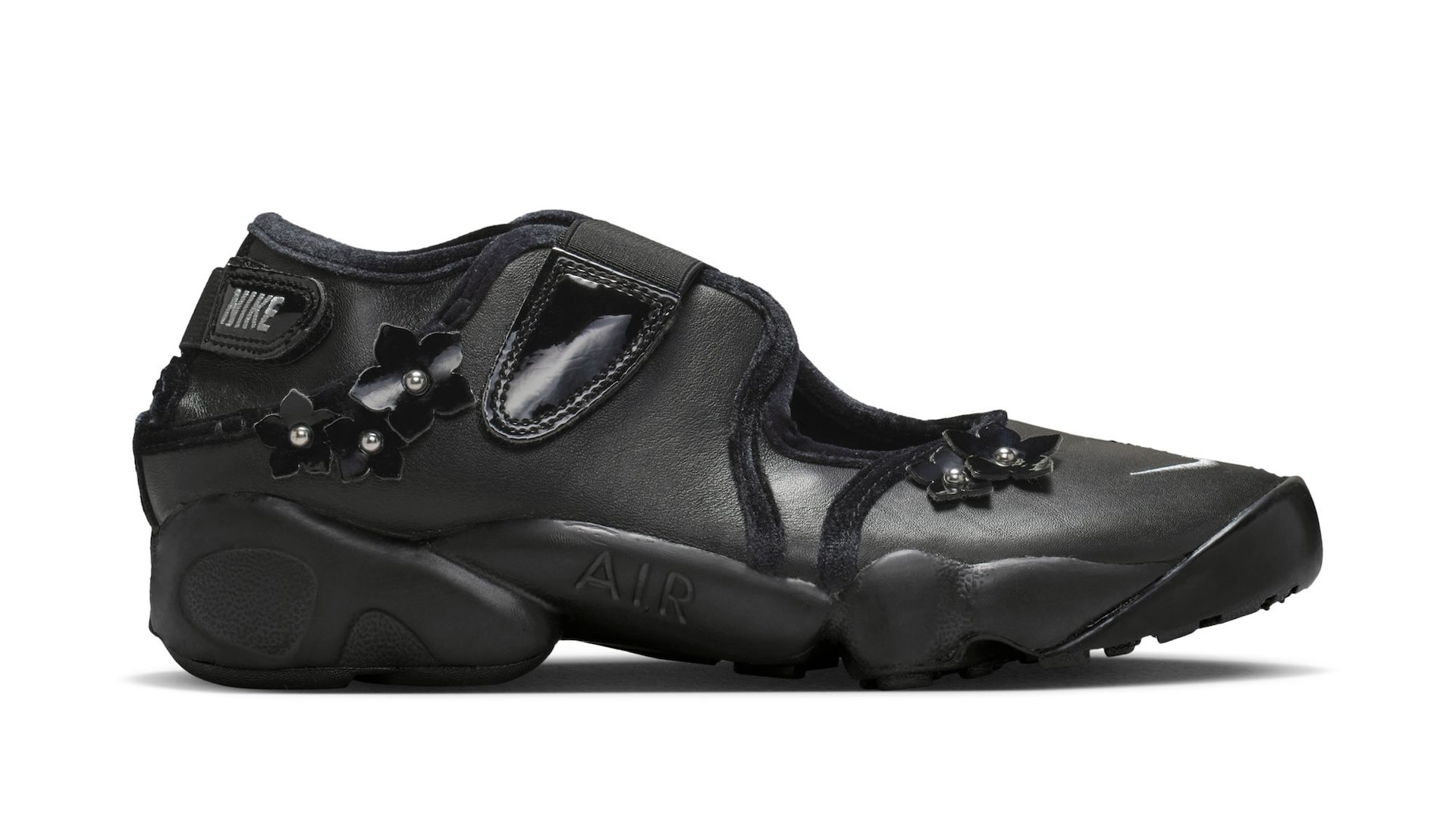 A black Nike sneaker with a unique design, featuring floral embellishments and a split-toe style.