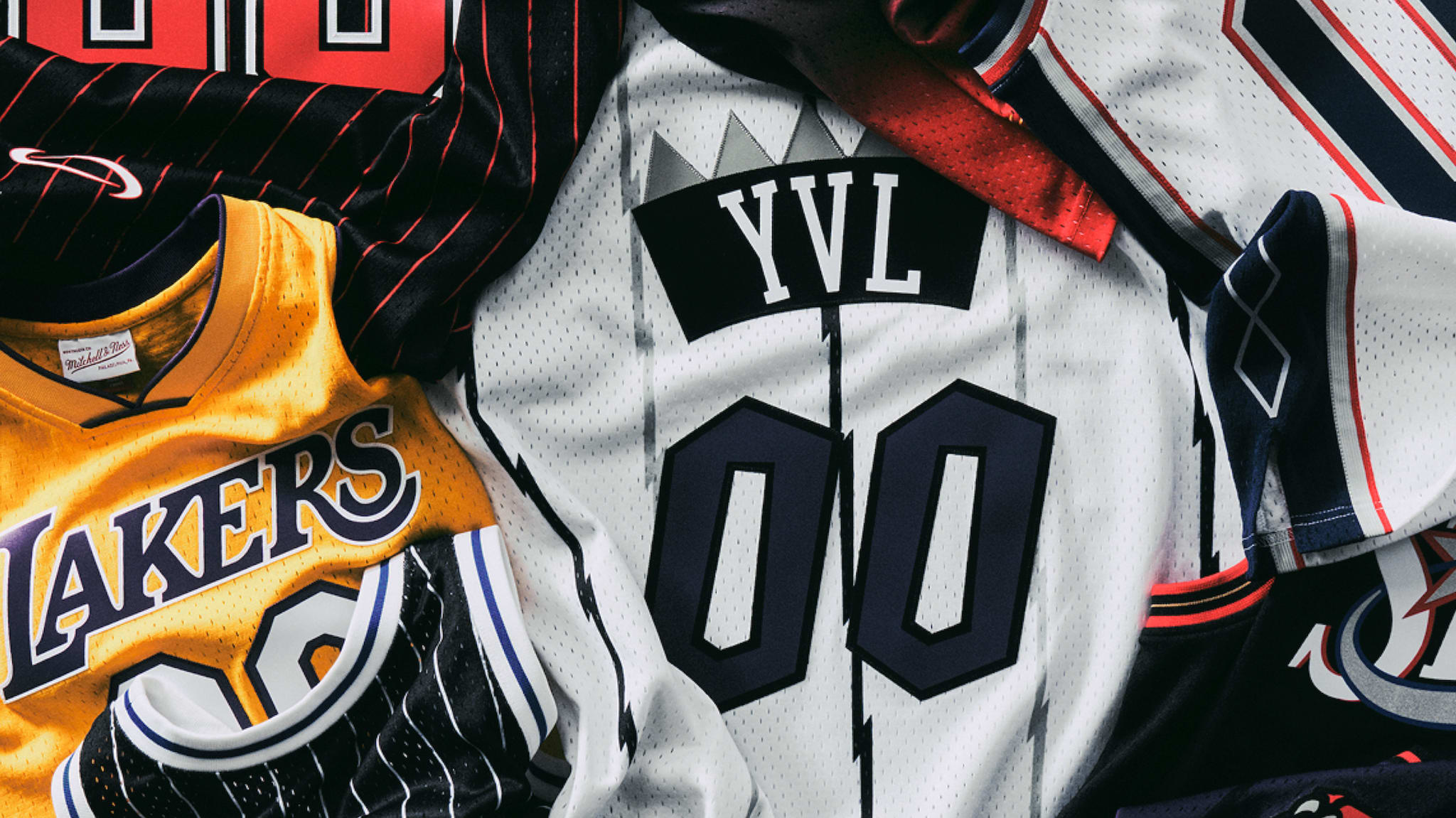 A collection of basketball jerseys, including a yellow Lakers jersey and a white jersey with "YVL" and "00" on it.