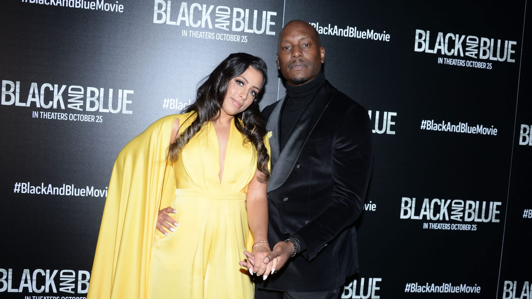 Tyrese Gibson in a black suit and Samantha Lee in a yellow dress at the "Black and Blue" movie premiere event.